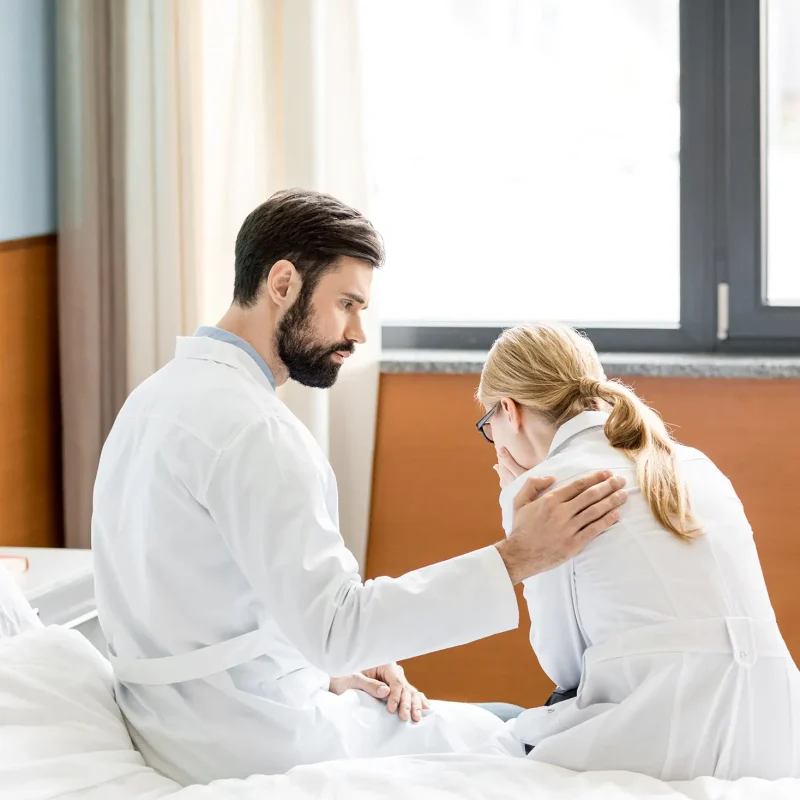 side view of doctor soothing upset colleague in hospital