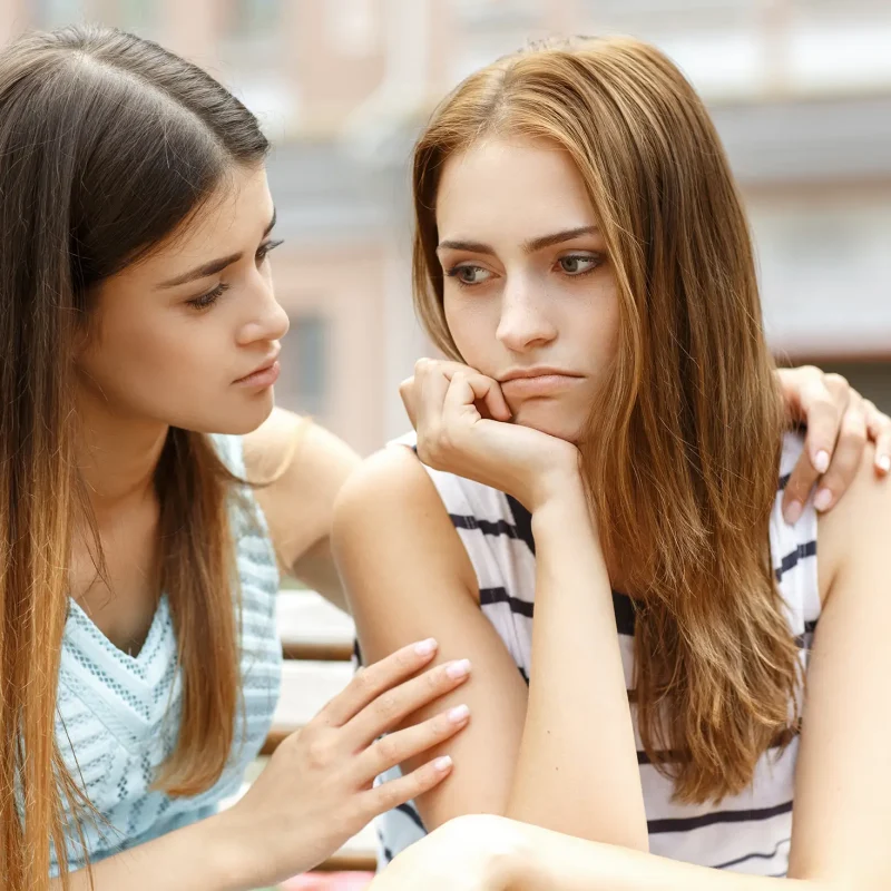I am here for you. Young beautiful female comforting her sad friend hugging her