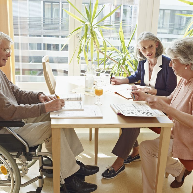 Germany, Cologne, Men on wheelchair with women sitting in nursing home