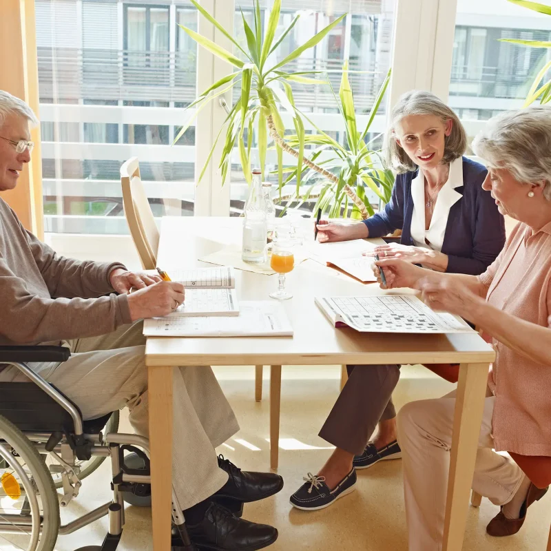 Germany, Cologne, Men on wheelchair with women sitting in nursing home