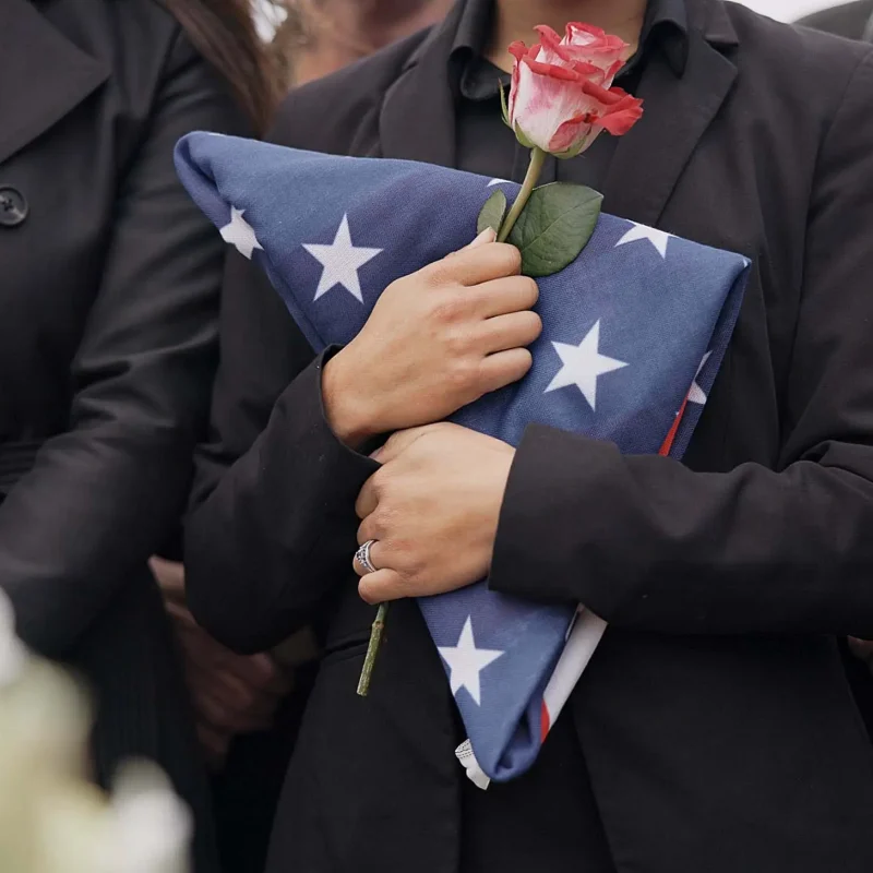 Funeral, graveyard and woman with American flag for veteran for respect, ceremony and memorial serv.